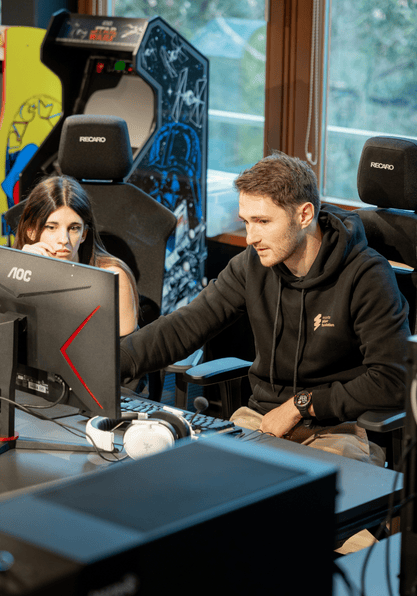 Maximilian Schaller zeigt auf einen Bildschirm - bringt so einem Talent league of legends bei