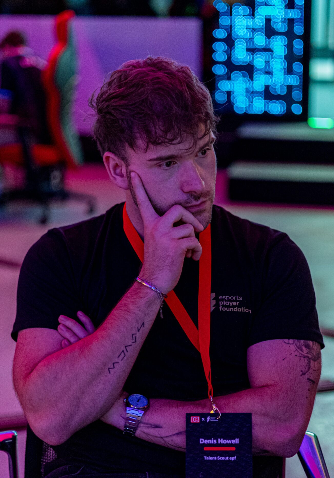 Denis "Denis" Howell Head of CS2, Momentaufnahme eines Events - Der Kopf ist seitlich gerichtet, eine Hand liegt an seinem Gesicht an. Er schaut einem Spieler beim Gamen zu