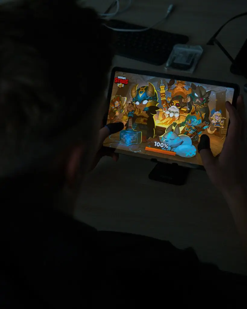 Ein Spieler sitzt vor seinem Tablet und spielt Brawl Stars - zu sehen ist der Loading Screen. Er hat zwei FIngersleeves an, die ihm mehr Grip erlauben.