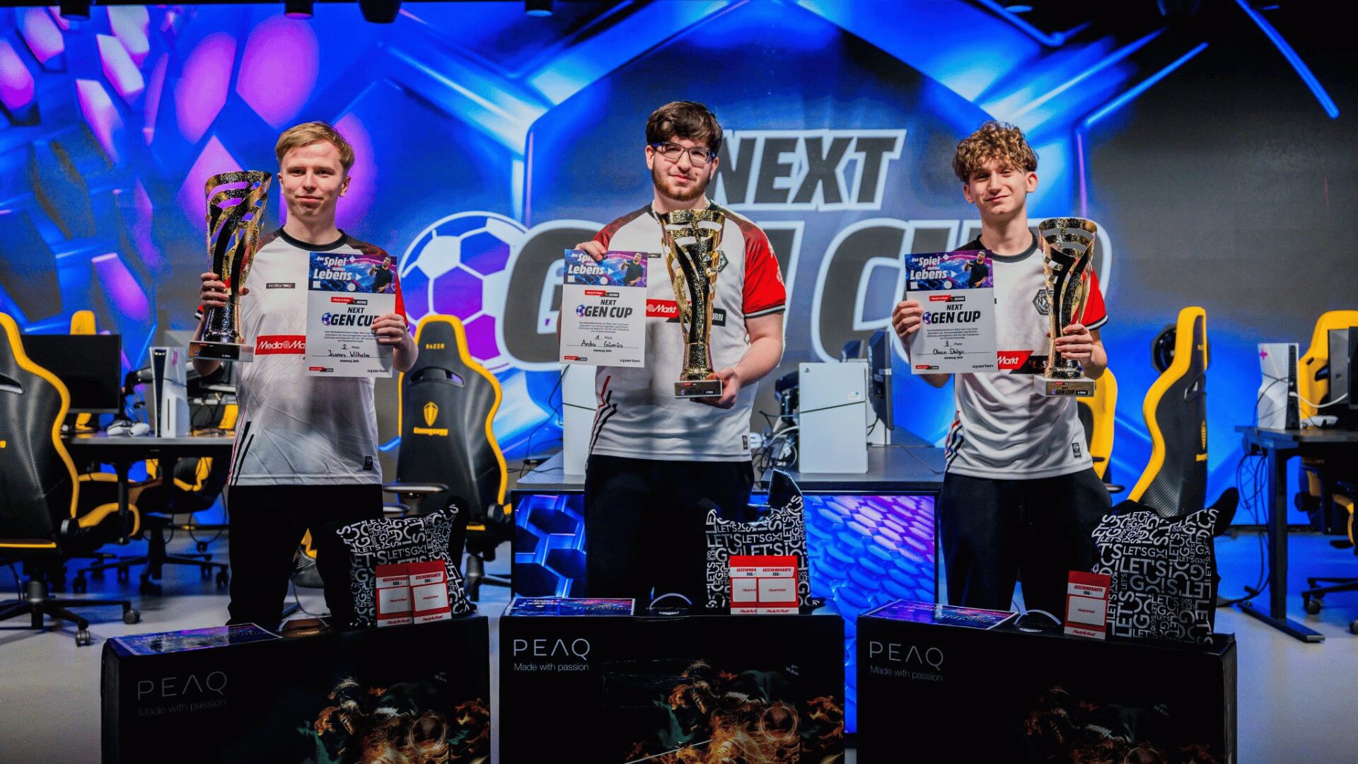 Die Gewinner des XPERION NXT Stipendium halten ihre Pokale welche sich nun am Ende des MediaMarktSaturn Next Gen Cups gewonnen haben in die Höhe. Die jungen EA FC Esports Talente tragen bereits die Trikots und stehen im XPERION Hamburg.