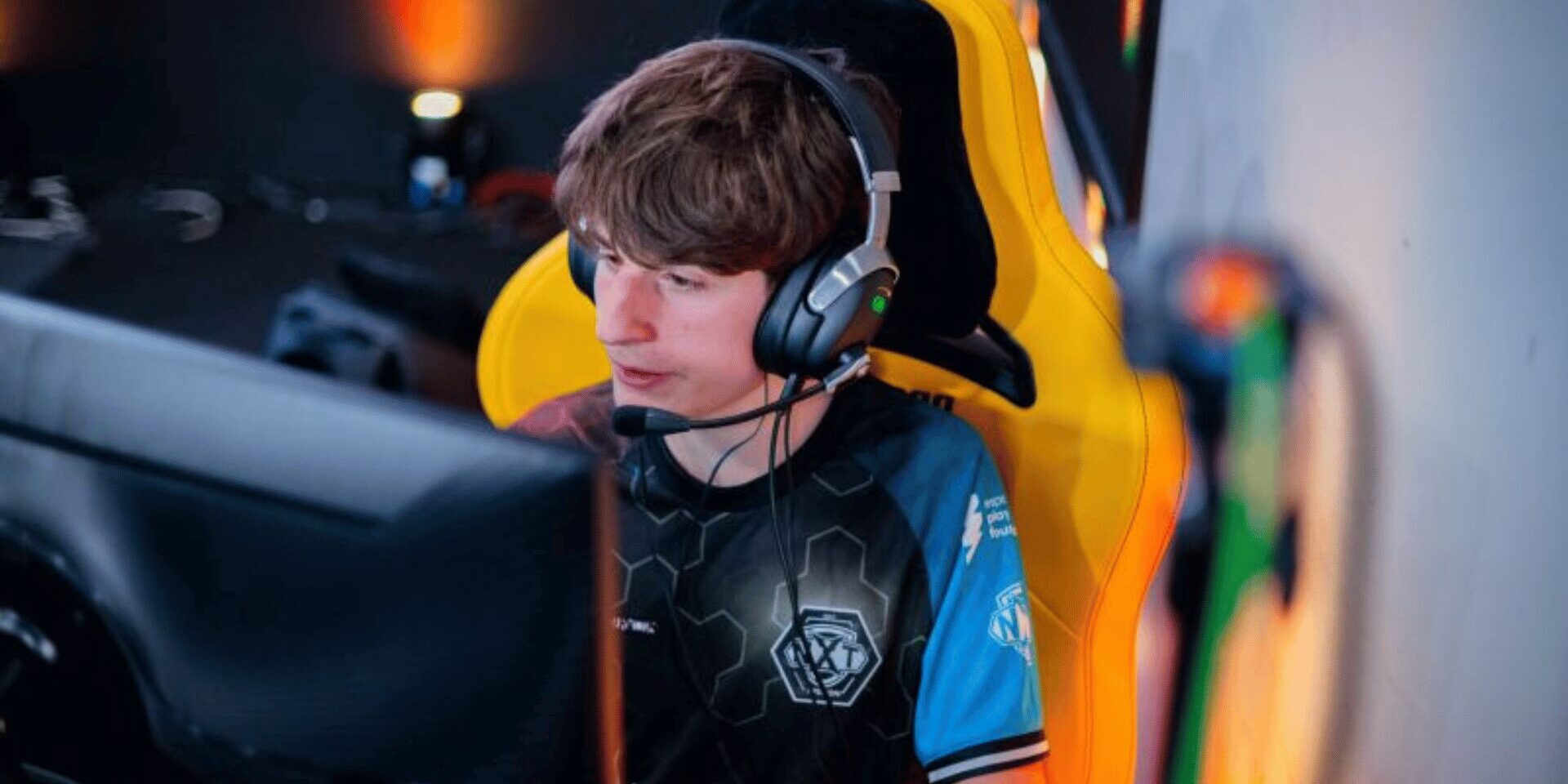 Robert van Treeck Newcomer des Jahres Robert van Treeck, Esports Spieler im Counter-Strike-2 Esports Team XPERION NXT sitzt in einem gelben Gaming Chair vor einem PC. Robert van Treeck, besser bekannt als Rhyzar trägt das XPERION NXT Trikot mit dem Logo der esports player foundation und anderer Marken.